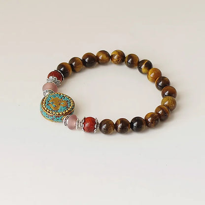 Bracelet tibétain Om porté au poignet perles oeil de tigre ambré