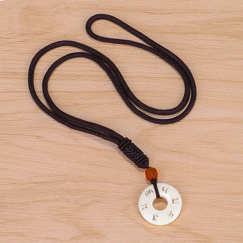 Pendentif bouddhiste tibétain ivoire synthétique porté sur tenue sobre